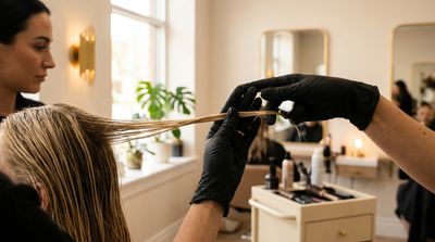 Colorista profissional avaliando o cabelo de uma cliente antes de um serviço de clareamento em salão moderno