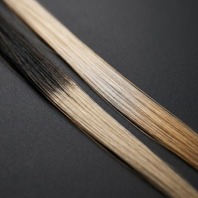 Duas mechas sobre fundo carvão: uma com raiz escura e linha de demarcação visível, outra com o tom desbotado para dourado