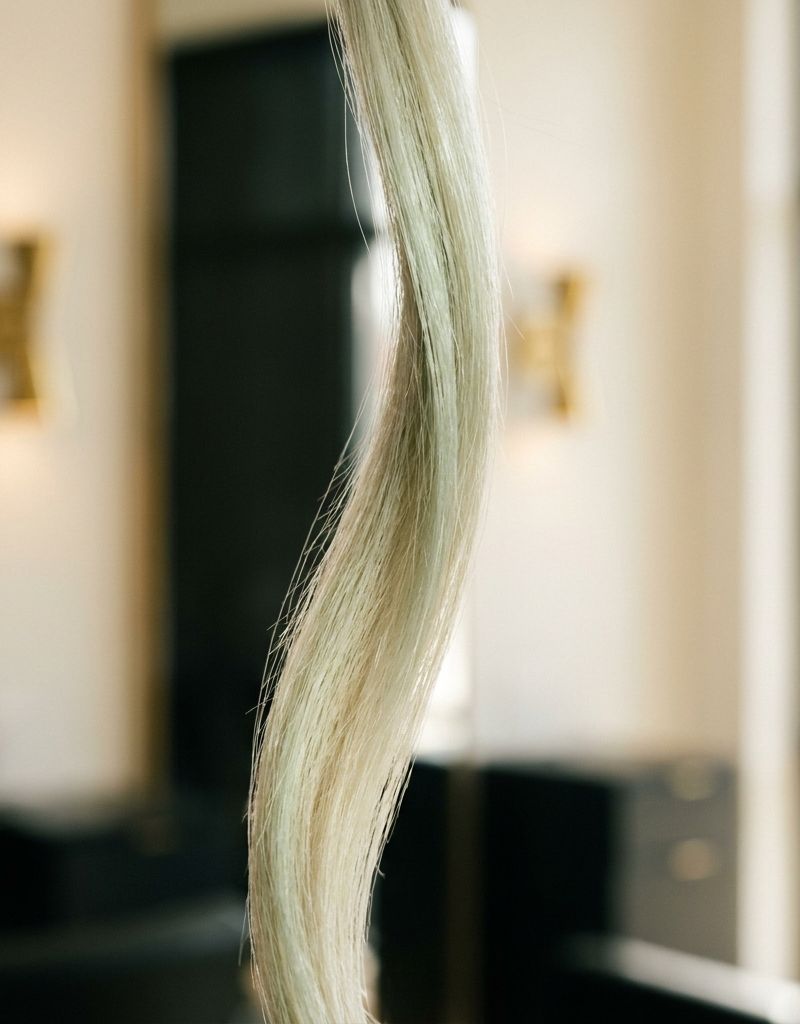 Mechón de cabello rubio decolorado con tonos verdosos antes y después de neutralización