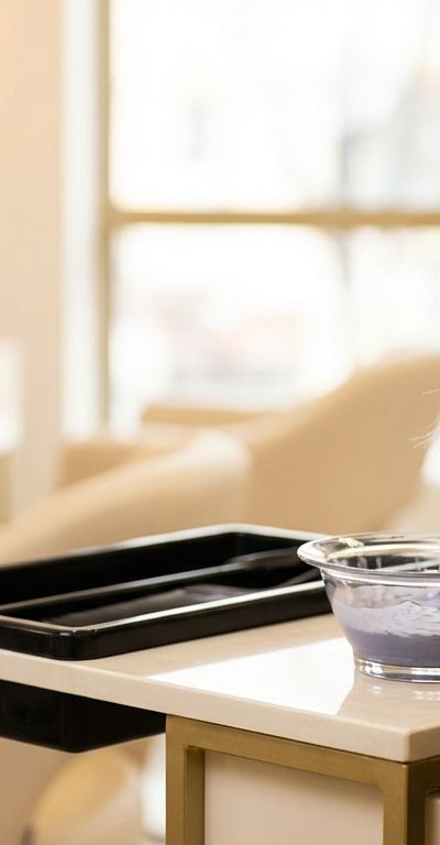 Professional colorist applying toner to bleached blonde hair next to an underlying pigment level reference chart