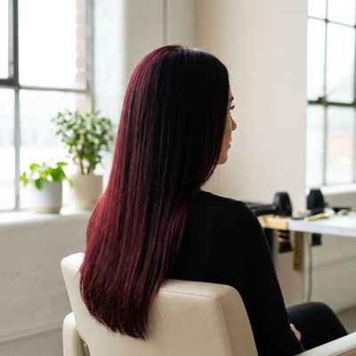 Cabelo em preto cereja visto sob a luz de uma janela, com o reflexo vermelho visível apenas nos meios