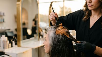 Colorista profissional aplicando pré-pigmentação quente em cabelo com fios brancos resistentes antes do processo de cor