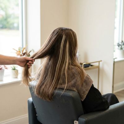 Cabelo com luzes antigas crescidas sobre a base natural, separado em mechas sobre o encosto da cadeira do salão