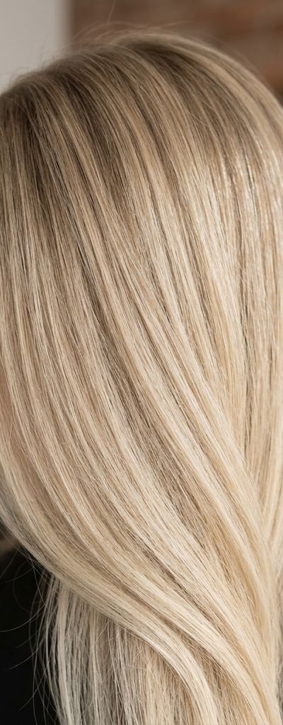 Cabello rubio arena de aspecto beige neutro con raíz sombreada suave en salón profesional