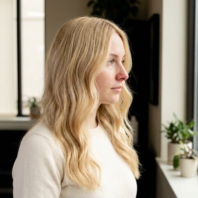Cabelo loiro manteiga de perfil perto de uma janela com luz da manhã, com o reflexo dourado cremoso visível nos meios e nas pontas