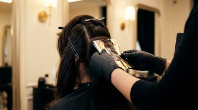 Colorista profissional colocando papel de foil na raiz para a técnica shadow root com foil