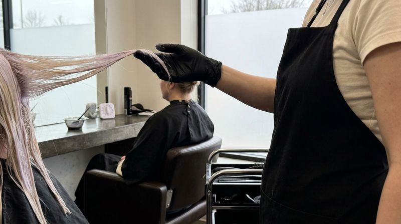 A gloved hand lifts a toner-coated section toward the window light to watch the porous areas, with a timer in the background