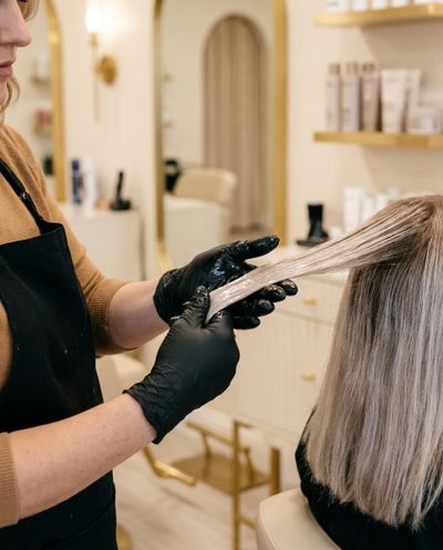 Coloristra selando a cutícula de um cabelo loiro no salão antes do verão